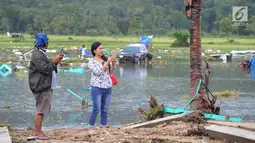 Warga berselfie dengan latar belakang kawasan terdampak bencana tsunami di Carita, Banten, Selasa (25/12). Libur Natal dimanfaatkan warga luar Anyer dan carita untuk menyaksikan langsung terdampak bencana sambil berselfie. (Merdeka.com/Arie Basuki)