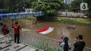 Fanani)
Warga menyaksikan pembentangan bendera Merah Putih di aliran kali
Ciliwung di kawasan Sudirman, Jakarta, Minggu (22/8/2021). Pembentangan atau pengibaran bendera Merah Putih tersebut dilaksanakan untuk memperingati HUT ke-76 RI. (Liputan6.com/Faizal Fanani)