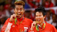 Pasangan ganda campuran Indonesia, Tontowi Ahmad dan Liliyana Natsir mengigit medali emas usai mengalahkan lawannya asal Malaysia Peng Soon Chan dan Liu Ying Goh pada final bulutangkis di Riocentro Pavilion 4 , Brasil. (REUTERS/Mike Blake)