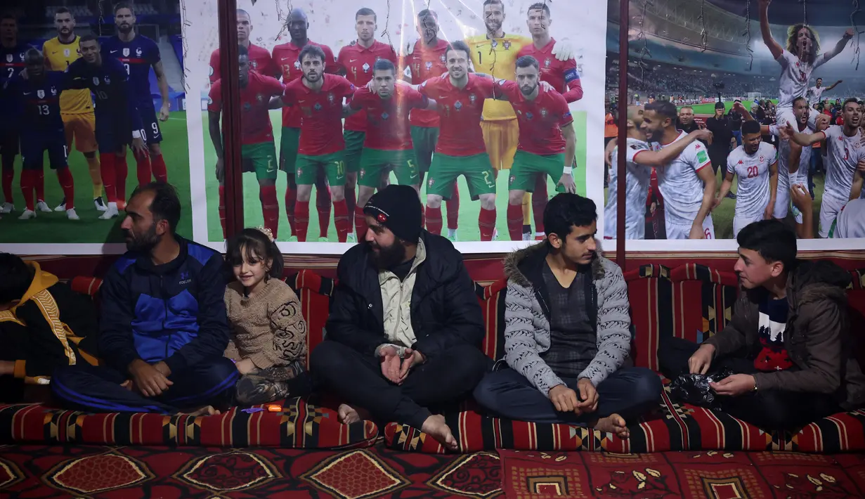Para pengungsi Suriah menonton pertandingan antara Maroko dan Portugal selama turnamen Piala Dunia Qatar 2022 di dalam tenda di kamp Barisha di bagian utara provinsi Idlib (10/12/2022). Acara nonton bareng ini diselenggarakan oleh sukarelawan organisasi kemanusiaan untuk para penggemar. (AFP/Omar Haj Kadour)