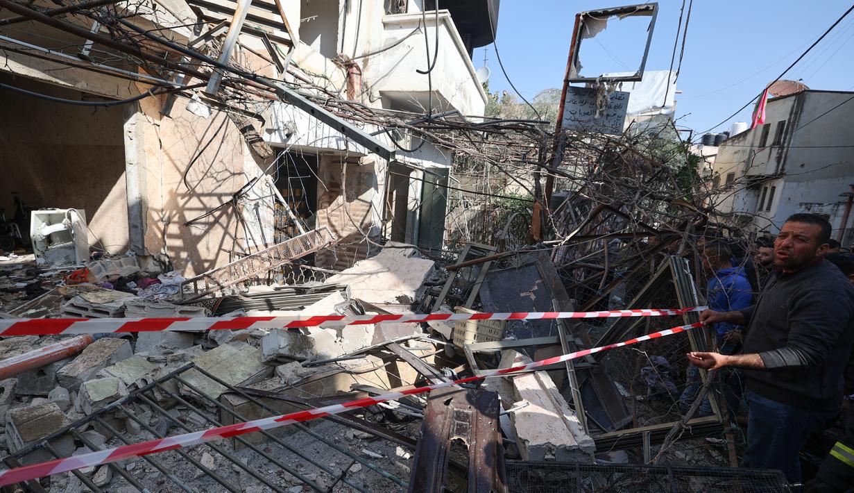 Orang-orang berkumpul di sekitar bangunan yang dirusak dan dibakar oleh pasukan Israel selama penggerebekan di kamp pengungsi Jenin Tepi Barat, pada 26 Januari 2023. Tentara Israel menggunakan gas air mata di dalam rumah sakit dan menolak berkomentar ketika ditanya oleh AFP tentang tuduhan gas air mata. (AFP/Jaafar Ashtiyeh)