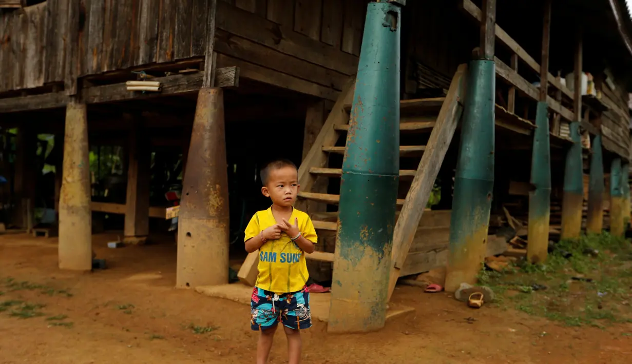 Anak laki-laki berdiri di depan rumah yang dibangun dari bom yang dijatuhkan oleh pesawat Angkatan Udara AS selama Perang Vietnam, di Desa Ban Napia, Provinsi Xieng Khouang, Laos (03/9). (REUTERS/Jorge Silva)