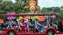 Para pengunjung duduk di dalam kendaraan yang melaju melewati struktur Dewa Keberuntungan yang dipasang sebagai persiapan menyambut Tahun Baru Imlek di sekitar jalur pengamatan hutan Supertrees di Gardens by the Bay, Singapura, pada tanggal 15 Januari 2024. (Roslan RAHMAN/AFP)