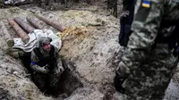 Seorang anggota tentara Ukraina memeriksa sebuah parit di base camp Rusia yang kosong di dekat Buda-Babynetska, utara Kiev, pada 5 April 2022, beberapa hari setelah pasukan Rusia mundur. (RONALDO SCHEMIDT / AFP)