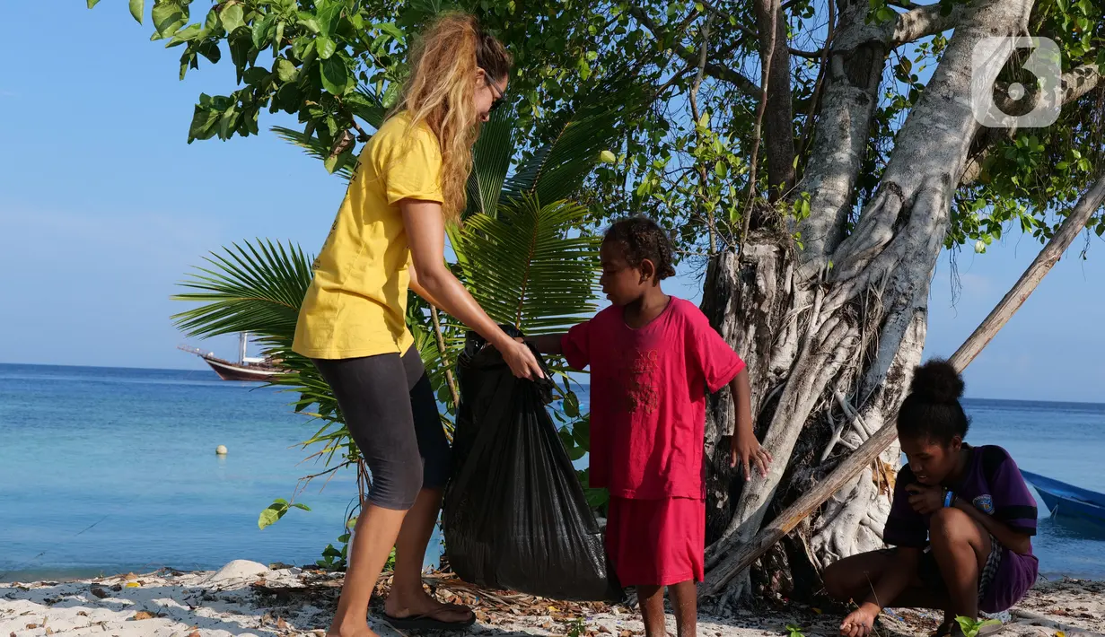 Aktivis AS, Carrie dan anak-anak membersihkan sampah plastik di bibir pantai Desa Sawandarek, Raja Ampat, Papua Barat (22/11/2019). Aksi membersihkan sampah plastik ini, digagas Carrie, aktivis asal Amerika Serikat,  yang sudah menetap di Indonesia selama 3 tahun. (Liputan6.com/Herman Zakharia)