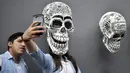 Seorang wanita berswafoto dengan replika tengkorak saat pameran dan kontes di perayaan Hari Kematian di Mexico City (1/11). Pameran dan kontes ini diadakan oleh Historic Center Foundation dalam rangka perayaan Hari Orang Mati. (AFP Photo/Yuri Cortez)