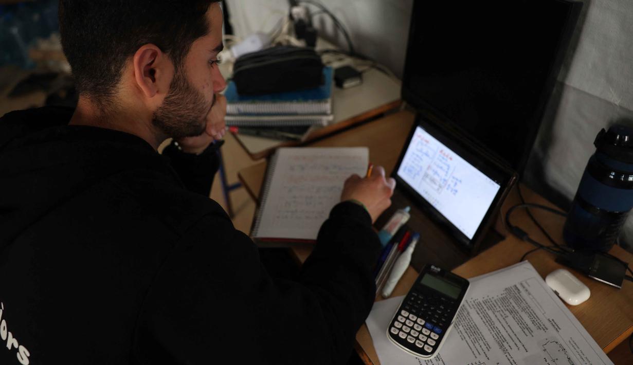 Untuk menjaga keberlangsungan pendidikan di tengah situasi keamanan yang tidak menentu, saat ini, proses belajar mengajar secara daring di Lebanon menjadi salah satu opsi utama. Tampak dalam foto, seorang pria Lebanon yang mengungsi melanjutkan studinya secara daring di sebuah sekolah negeri yang diubah menjadi tempat penampungan, di kota Dekwaneh, utara Beirut pada Rabu 25 Maret 2026. (Anwar AMRO/AFP)