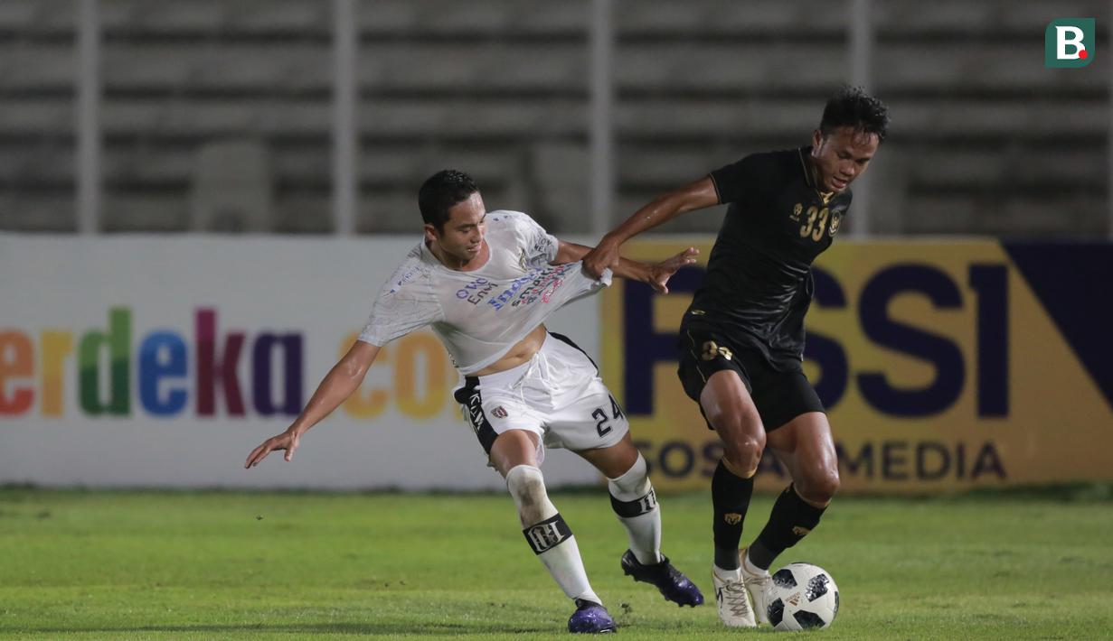 Bek Bali United, Ricky Fajrin, saat berebut bola dengan bek Timnas Indonesia pada laga uji coba di Stadion Madya, Minggu (7/3/2021). (Bola.com/ Ikhwan Yanuar Harun)