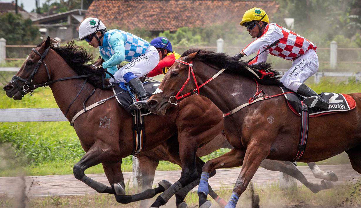 Berlokasi di Lapangan Pacuan Kuda Sultan Agung, kompleks Stadion Sultan Agung (SSA) di Bantul, Daerah Istimewa Yogyakarta, sekitar 120 kuda dari 18 kelas berpacu untuk menjadi yang tercepat. Tampak dalam foto, joki-joki berkompetisi dalam kejuaraan balap kuda nasional tahunan yang memperebutkan trofi Sultan Hamengku Buwono X, di lintasan Sultan Agung, Bantul, Yogyakarta, pada Minggu 9 November 2025. (DEVI RAHMAN/AFP)