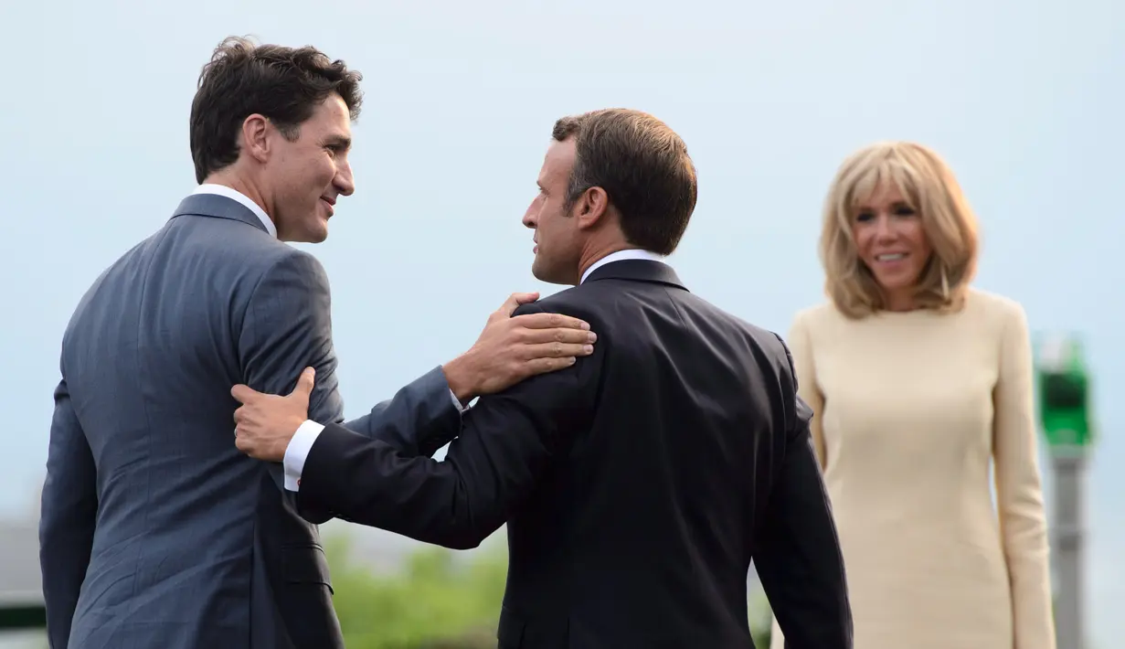 Presiden Prancis Emmanuel Macron (tengah) disaksikan istrinya Brigitte Macron (kanan) menyambut kedatangan Perdana Menteri Kanada Justin Trudeau (kiri) di KTT G7, Biarritz, Prancis, Sabtu (24/8/2019). (Sean Kilpatrick/The Canadian Press via AP)