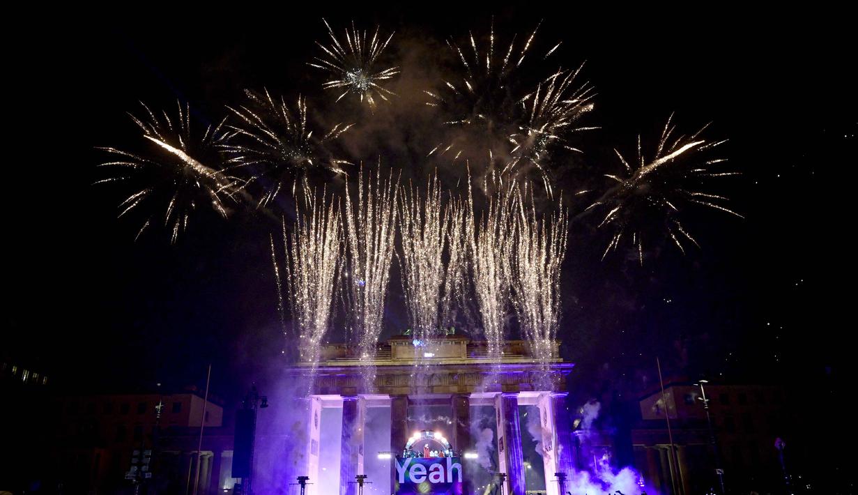 Orang-orang merekam dan memotret dengan ponsel mereka saat kembang api meledak di atas landmark Berlin, Gerbang Brandenburg, Berlin pada 1 Januari 2026. (John MACDOUGALL/AFP)