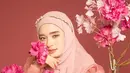 Berpose topang dagu, Inara tampil cantik dengan dress organza warna coral dengan aksen  puff sleeve. Dress tersebut dipadukan dengan hijab dan bando mutiara. [Foto: IG/inararusli/dierabachir].