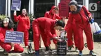 Sejumlah aktivis Indonesia Corruption Watch (ICW) dan Gerakan #BersihkanIndonesia melakukan aksi teatrikal saat unjuk rasa di depan Gedung KPK, Jakarta, Rabu (8/12/2021). Aksi dalam rangka memperingati Hari Anti Korupsi Sedunia pada 9 Desember 2021. (Liputan6.com/Herman Zakharia)