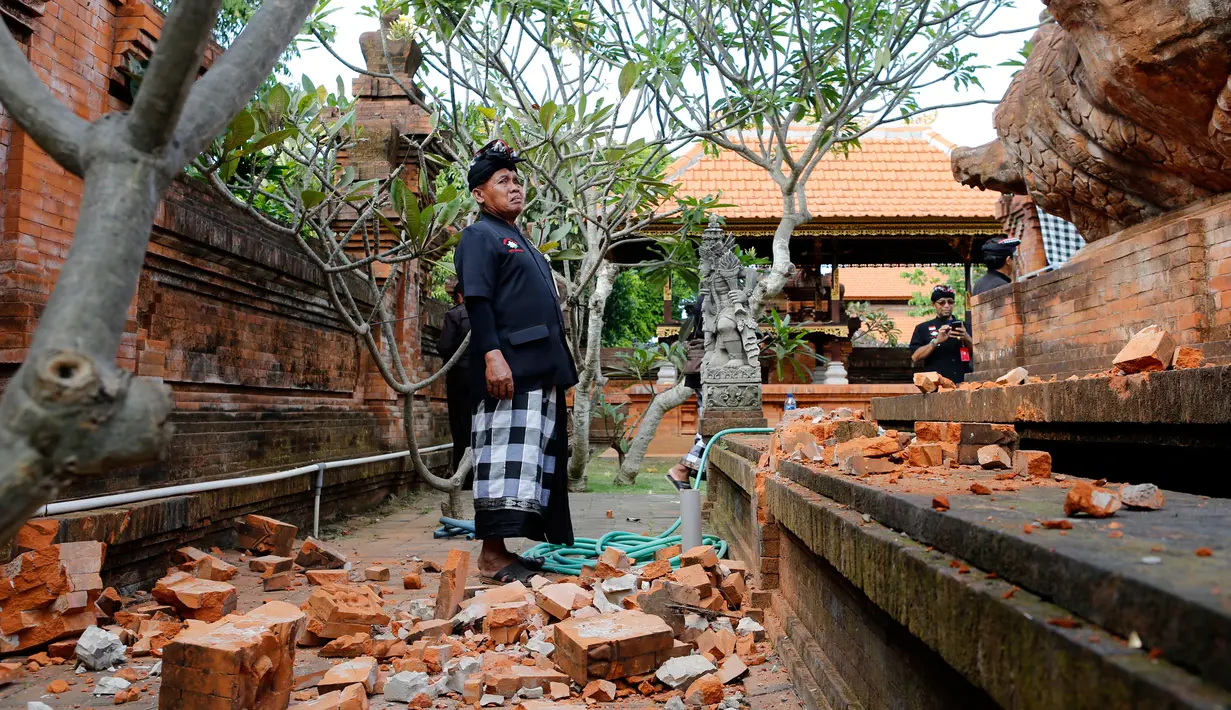 Pemuka agama memantau kerusakan pada bagian candi yang runtuh akibat gempa di Pura Lokanatha, Denpasar, Bali, Selasa (16/7/2019). Gempa Magnitudo 5,8  yang mengguncang Bali tidak menimbulkan korban jiwa, tapi sejumlah bangunan di beberapa kawasan mengalami kerusakan. (AP/Firdia Lisnawati)