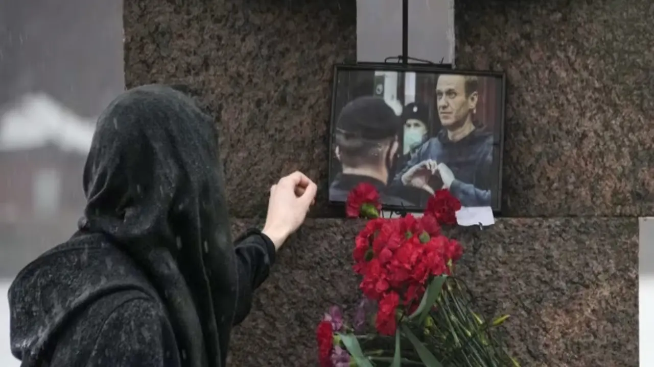 Wanita sentuh foto Alexei Navalny setelah meletakkan bunga sebagai penghormatan terakhir di  Memorial to Victims of Political Repression di St Petersburg, Rusia pada 17 Februari 2024. (AP/Dmitri Lovetsky)