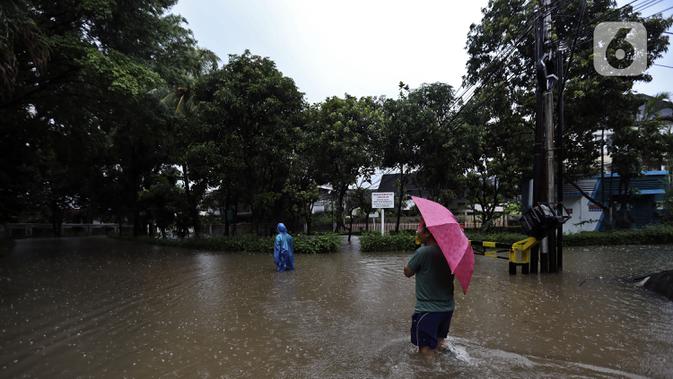 Warga melintasi banjir di Jalan Hang Lekir, Kebayoran Lama, Jakarta Selatan, Rabu (1/1/2020). Banjir tersebut disebabkan karena tingginya intensitas hujan yang mengguyur sejak Selasa (31/12/2019). (Liputan6.com/Johan Tallo)