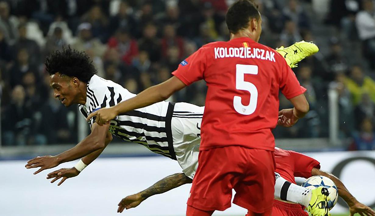Pemain Juventus, Juan Cuadrado terjatuh saat berebut bola dengan pemain Sevilla pada laga Liga Champions di Stadion Juventus, Italia, Kamis (1/10/2015). (AFP Photo/Olivier Morin)