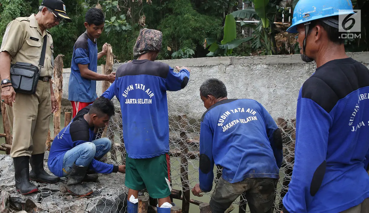 Petugas gabungan merekatkan kawat saat memperbaiki tanggul yang jebol di Kelurahan Jatipadang, Jakarta, Selasa (12/12). Tanggul sementara yang terbuat dari karung pasir dan batu kali tersebut direkatkan dengan kawat. (Liputan6.com/Immanuel Antonius)