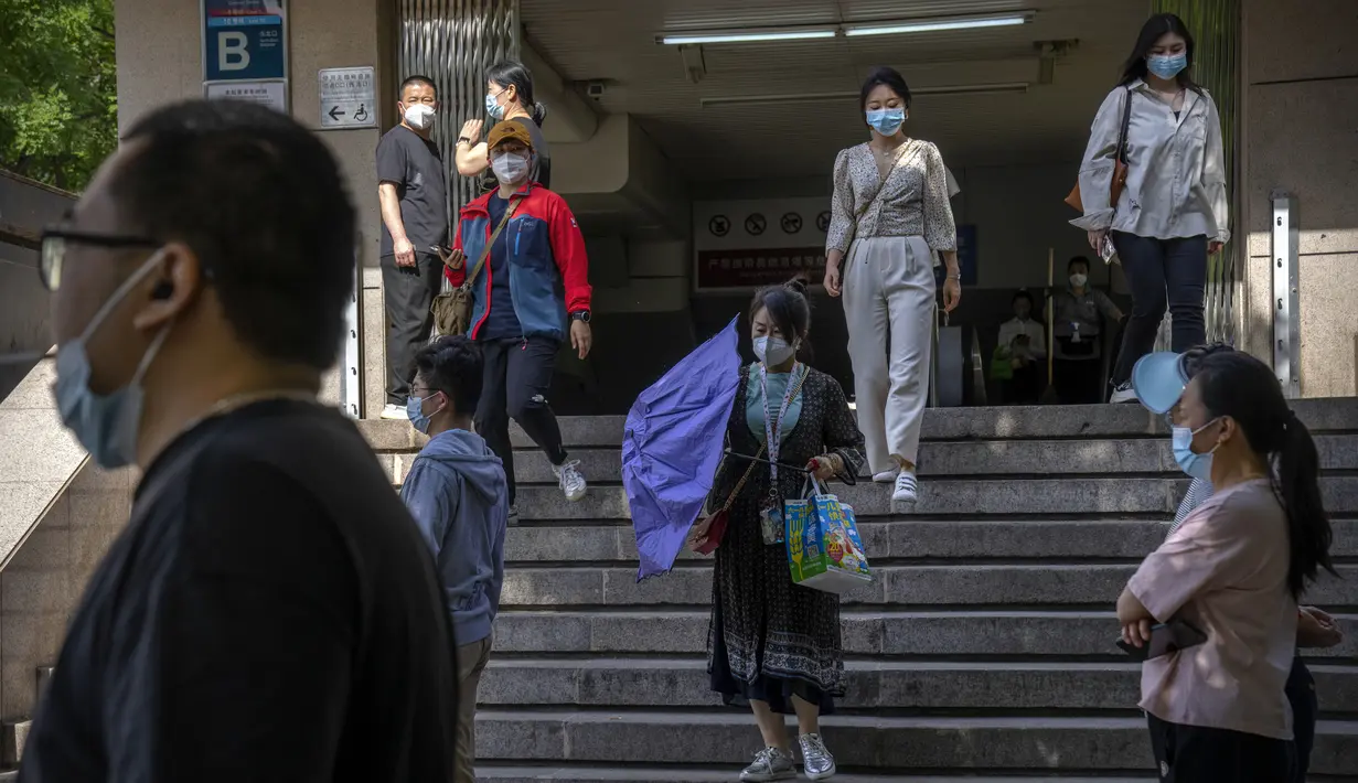 Para komuter yang mengenakan masker berjalan menuruni tangga di stasiun kereta bawah tanah yang baru dibuka kembali di kawasan pusat bisnis di Beijing, China, Selasa (31/5/2022). Otoritas Shanghai mengatakan mereka akan mengambil beberapa langkah besar pada Rabu untuk membuka kembali kota terbesar di China setelah dua bulan penguncian COVID-19. (AP Photo/Mark Schiefelbein)