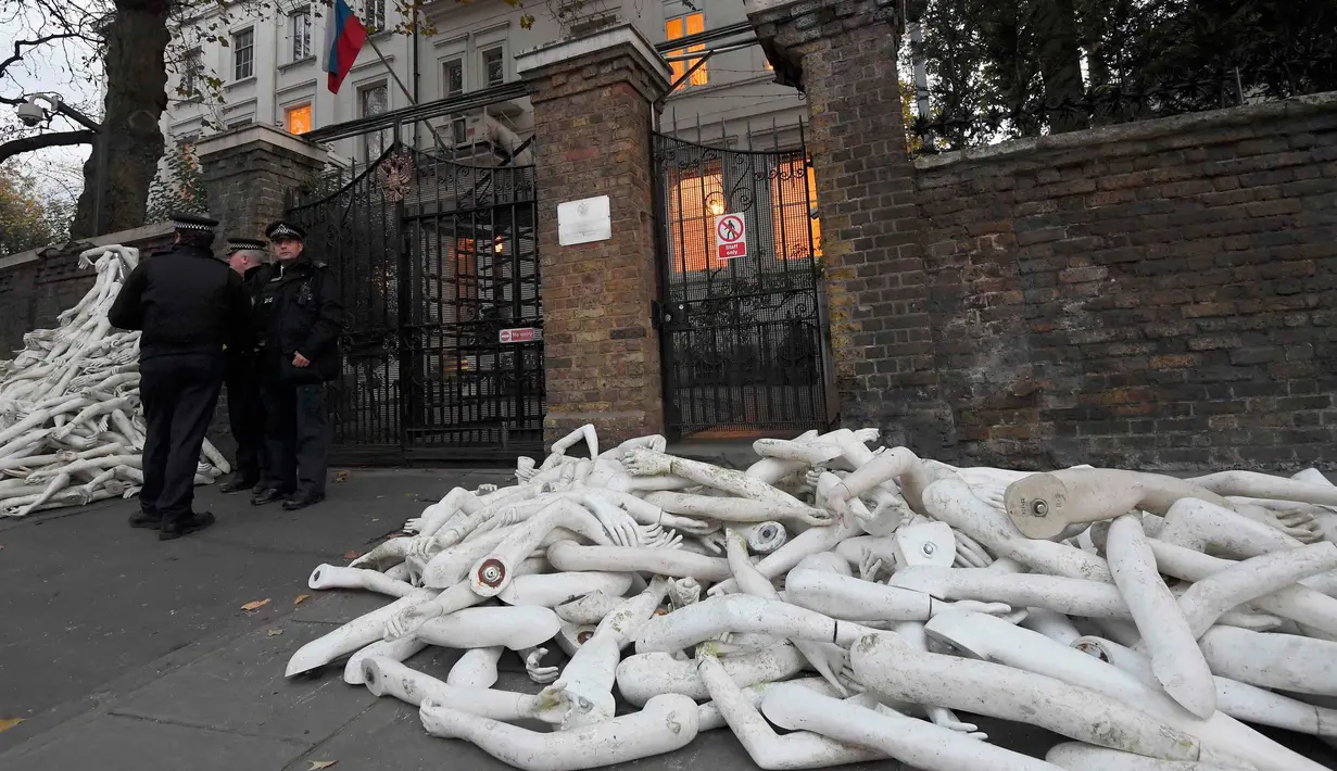 Petugas keamanan mengamati tumpukan lengan manekin di depan pintu masuk Kedutaan Besar (Kedubes) Rusia di London, Kamis (3/11). Pengunjuk rasa mengklaim lengan-lengan plastik itu mewakili luka-luka yang dialami warga Aleppo Suriah. (REUTERS/Toby Melville)