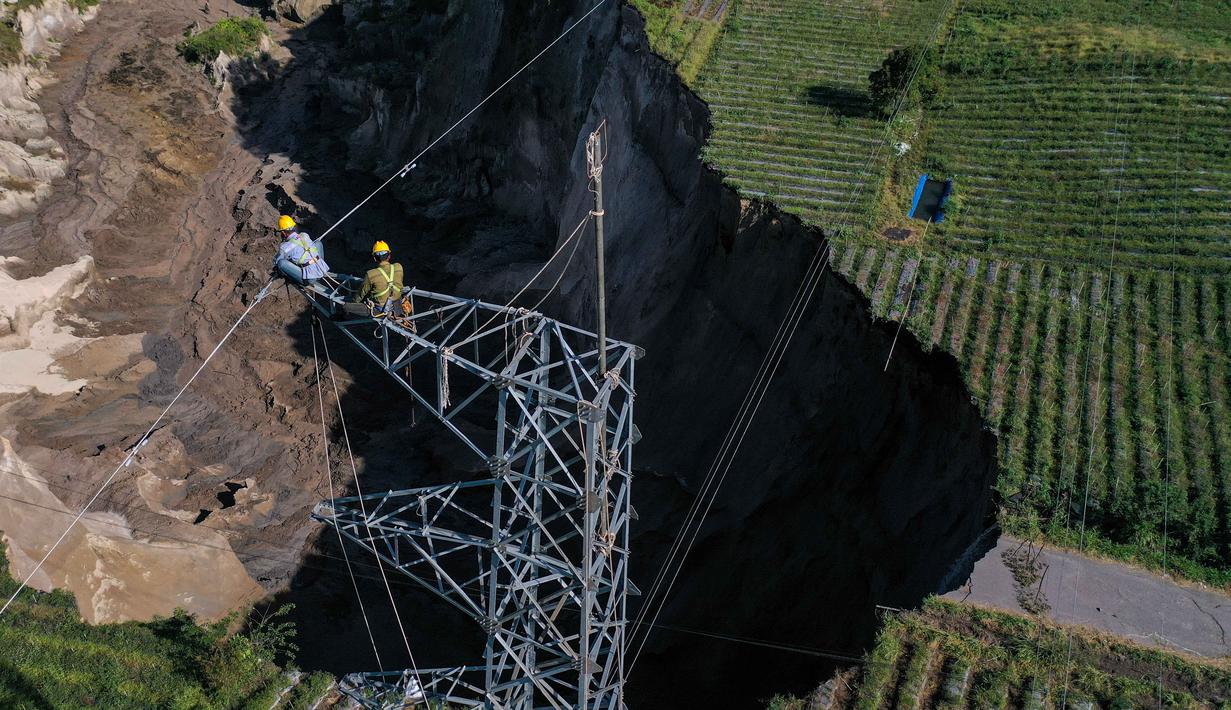 Selain memutus jalan, longsoran ini kini sangat dekat dengan menara SUTET (Saluran Udara Tegangan Tinggi) milik PLN, yang berisiko mengganggu pasokan listrik di wilayah Aceh Tengah dan Bener Meriah. Tampak foto udara menunjukkan para pekerja dari perusahaan listrik negara Indonesia, PLN, mematikan operasi di menara transmisi tegangan tinggi dekat lokasi longsor di Desa Pondok Balik, Kecamatan Ketol, Aceh Tengah, provinsi Aceh pada 1 Februari 2026. (Fadly/AFP)