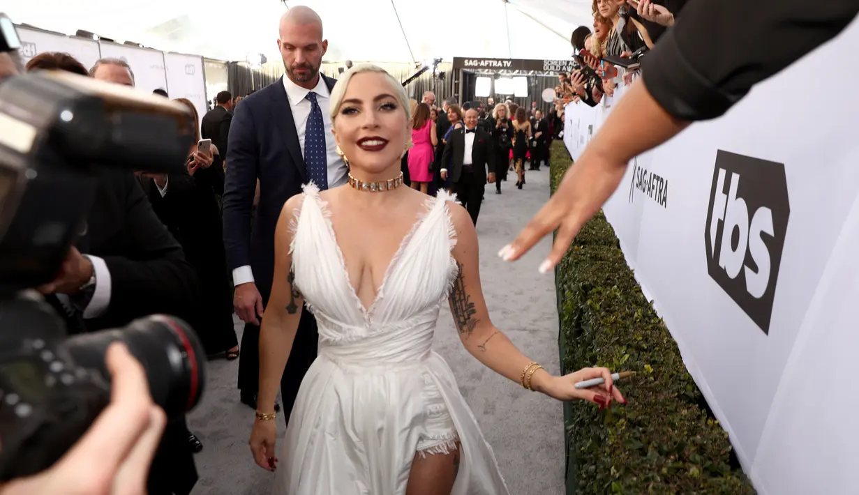 Lady Gaga menyapa penggemar saat menghadiri acara 25th Screen Actors Guild Awards di Los Angeles, California, AS (28/1). Lady Gaga tampil anggun menggenakan gaun putih dengan belahan hingga paha kreasi Dior Haute Couture. (AP Photo/Jordan Strauss)