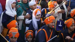 Anak-anak menonton atraksi yang ditampilkan prajurit Sikh selama prosesi keagamaan menjelang ulang tahun kelahiran Guru Gobind Singh di Jammu, India (2/1). Guru Gobind Singh juga seorang prajurit, penyair dan filsuf. (AP Photo / Channi Anand)