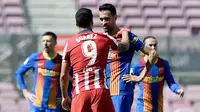 Striker Atletico Madrid, Luis Suarez, berbincang dengan gelandang Barcelona, Sergio Busquets, pada laga Liga Spanyol di Stadion Camp Nou, Sabtu (8/5/2021). Kedua tim bermain imbang 0-0. (AFP/Josep Lago)