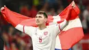 Pemain Timnas Denmark, Andreas Christensen, melakukan selebrasi dengan mengibarkan bendera nasional. Denmark jadi tim pertama dalam sejarah Piala Eropa yang lolos ke babak knockout setelah kalah di dua laga pertamanya di fase grup. (Jonathan Nackstrand/Pool via AP)