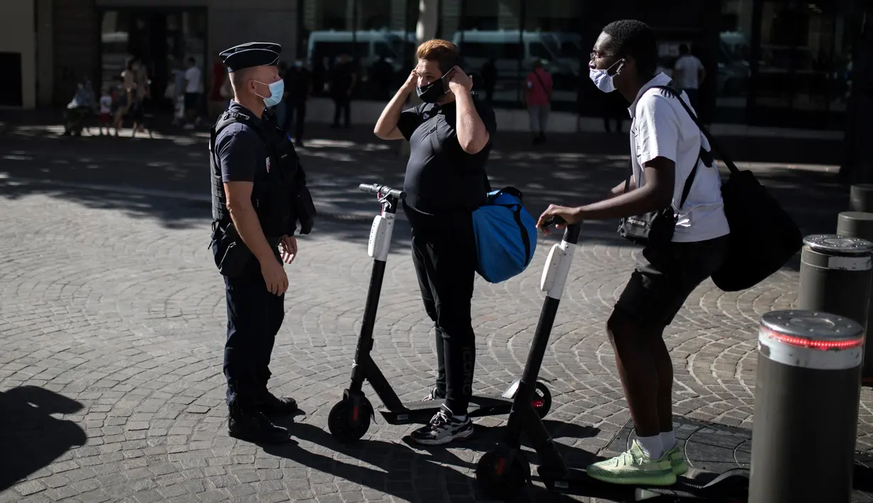 Polisi anti huru-hara memberi informasi tentang kewajiban penggunaan masker kepada warga di Marseille, Selasa (18/8/2020). Pemerintah Prancis mengirim polisi anti huru hara untuk membantu menegakkan peraturan penggunaan masker saat negara itu mencatat lonjakan kasus COVID-19. (AP Photo/Daniel Cole)