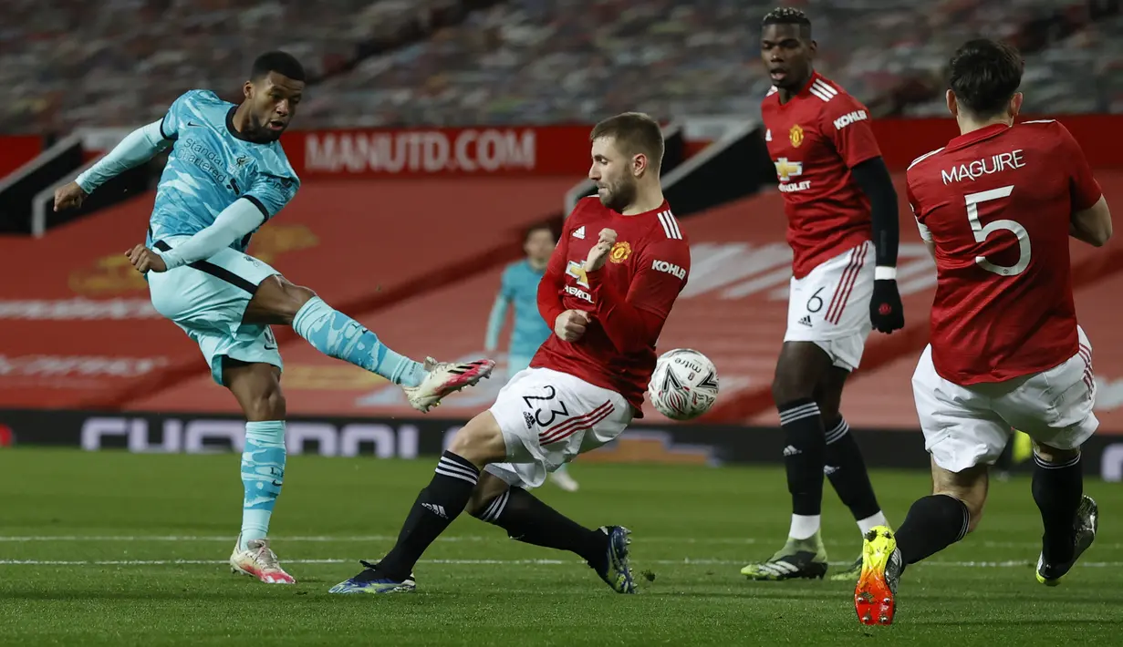 Gelandang Liverpool, Georginio (kiri) Wijnaldum menendang bola yang dihalangi oleh bek Manchester United, Luke Shaw dalam laga putaran keempat Piala FA di Stadion Old Trafford, Senin dinihari WIB (25/1/2021). Manchester United atau MU singkirkan Liverpool usai menang 3-2. (Phil Noble/Pool via AP)