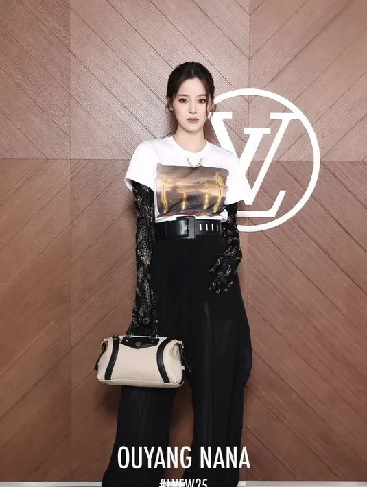 Ouyang Nana mengenakan atasan t shirt putih dipadukan inner lace serta belt besar hitam senada dengan warna celana panjangnya. Membawa tas warna beige. [dok. Louis Vuitton]