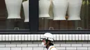 Seorang pekerja konstruksi yang mengenakan masker untuk membantu mengekang COVID-19 berjalan melewati sebuah toko pakaian di Tokyo, Jepang, Senin (2/11/2020). Tokyo mengonfirmasi lebih dari 80 kasus baru COVID-19 pada 2 Oktober 2020. (AP Photo/Eugene Hoshiko)