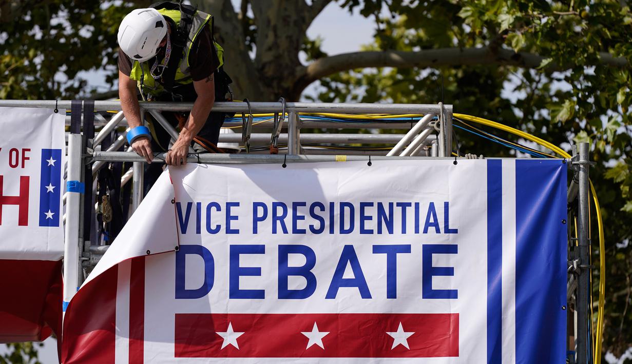 Pekerja memasang spanduk saat persiapan lanjutan untuk debat calon wakil presiden AS di luar Kingsbury Hall, Universitas Utah di Salt Lake City, Senin (5/10/2020). Debat cawapres petahana Mike Pence dan Senator California Kamala Harris akan digelar pada 7 Oktober. (AP Photo/Patrick Semansky)