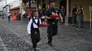 Pramusaji dan seorang anak beradu kecepatan sambil membawa nampan dalam Waiters Race ke-16 di Antigua, barat daya Ibu Kota Guatemala City, Rabu (14/11). Lomba ini diikuti oleh ratusan peserta yang merupakan pelayan restoran dan kafe. (JOHAN ORDONEZ/AFP)