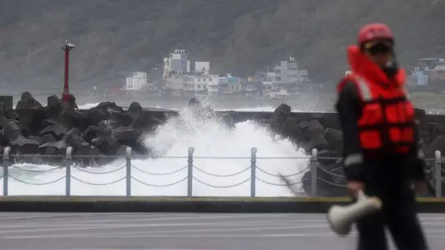 Seorang penjaga pantai bertugas saat ombak menghantam dinding penahan ombak saat Topan Super Kong-rey bergerak menuju Taiwan, di Keelung pada 31 Oktober 2024. (Foto: AFP/I-Hwa Cheng)