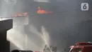 Petugas pemadam kebakaran berusaha memadamkan api yang membakar Gudang JNE Express di Jalan Pekapuran Raya, Depok, pada Senin (12/9/2022).  Besarnya api kebakaran gudang JNE pun membuat asap membumbung tinggi ke udara. (Liputan6.com/Herman Zakharia)