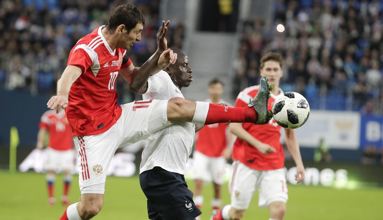 Striker Rusia, Fyodor Smolov, berebut bola dengan gelandang Prancis, N'Golo Kante, pada laga persahabatan di Stadion St Petersburg, Rusia, Selasa (27/3/2018). Rusia kalah 1-3 dari Prancis. (AP/Dmitri Lovetsky)