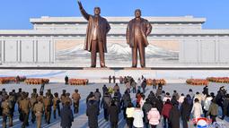 Warga dan tentara membawa bunga ke patung perunggu mantan Presiden Kim Il Sung dan mantan Ketua Kim Jong Il pada kesempatan peringatan 80 tahun kelahiran Kim Jong Il, di Pyongyang (16/2/2022). (AFP/KCNA Via KNS/STR)