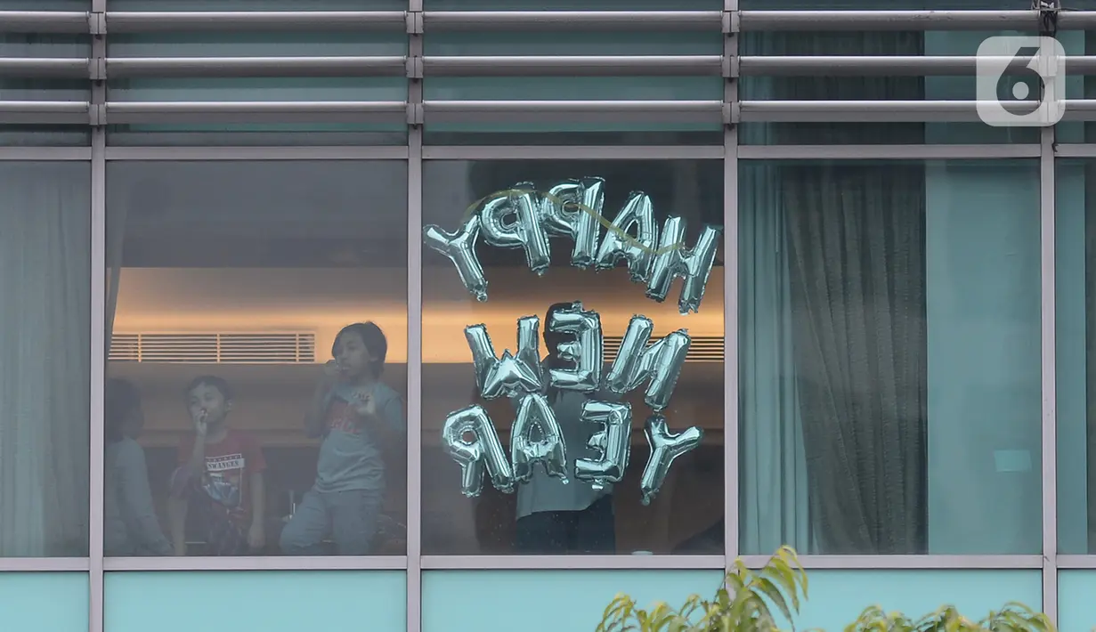 Tamu berdiri di jendela salah satu kamar hotel yang dipasangi tulisan “Happy New Year” di Bundaran HI, Jakarta, Kamis (31/12/2020). Hotel menjadi alternatif bagi warga yang untuk merayakan pergantian malam Tahun Baru. (merdeka.com/Imam Buhori)