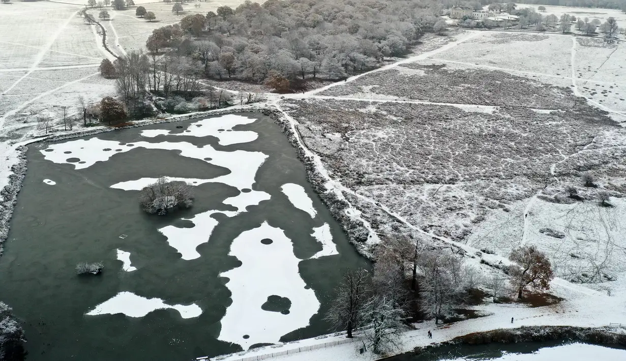 Pemandangan udara menunjukkan danau beku, dengan area tertutup salju di Richmond Park, London barat daya pada  Senin (10/12/2022). Salju dan es telah menyapu sebagian Inggris, dengan suhu dingin dan kabut yang membekukan serta salju diperkirakan akan tetap ada sepanjang minggu ini. (Daniel LEAL / AFP)