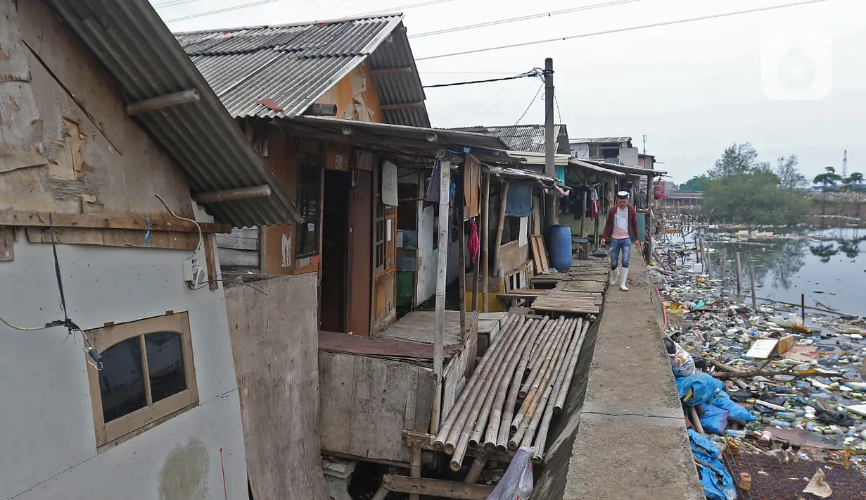 Warga berjalan melintasi sejumlah rumah di kawasan Kampung Tembok, Muara Angke, Jakarta Utara, Rabu (4/3/2020). Warga Kampung Tembok terpaksa harus menembok dan menutup akses jalan warga karena saat musim hujan kerap terjadi rob. (Liputan6.com/Herman Zakharia)