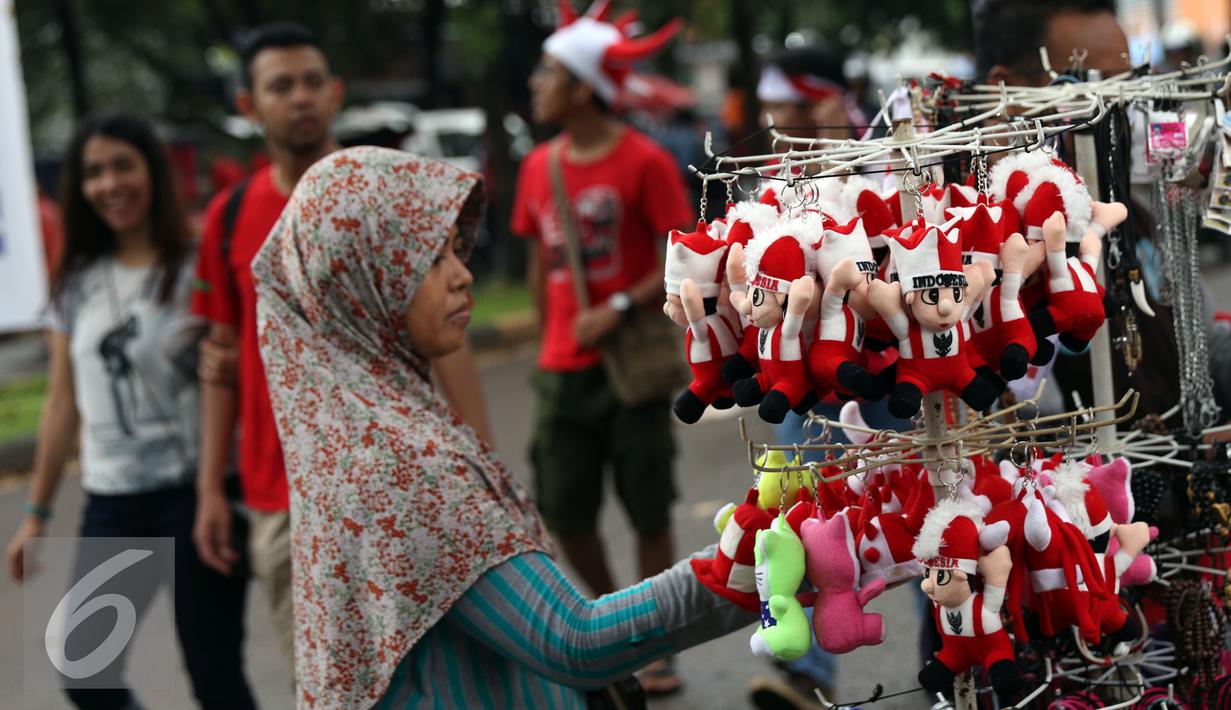 Warga memilih pernak pernik Timnas Indonesia di sekitar Stadion Pakansari, Bogor, Sabtu (3/12). Timnas Indonesia akan melakoni laga semifinal pertama Piala AFF 2016 melawan Vietnam. (Liputan6.com/Helmi Fithriansyah)
