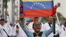 Para pengunjuk rasa mengecam tindakan Amerika Serikat yang dianggap melanggar kedaulatan Venezuela. Tampak dalam foto, seorang wanita memegang bendera nasional Venezuela selama pawai dukungan untuk mantan Presiden Venezuela Nicolas Maduro yang diselenggarakan oleh para pekerja di Caracas pada 14 Januari 2026. (Pedro MATTEY/AFP)