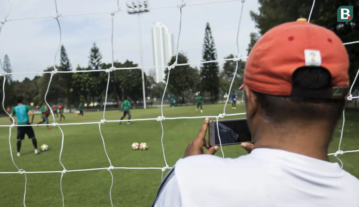 Seorang warga merekam suasana latihan Timnas Indonesia di Lapangan ABC Senayan, Jakarta, Minggu (18/3/2018). Latihan ini merupakan persiapan jelang laga uji coba melawan Singapura. (Bola.com/Vitalis Yogi Trisna)