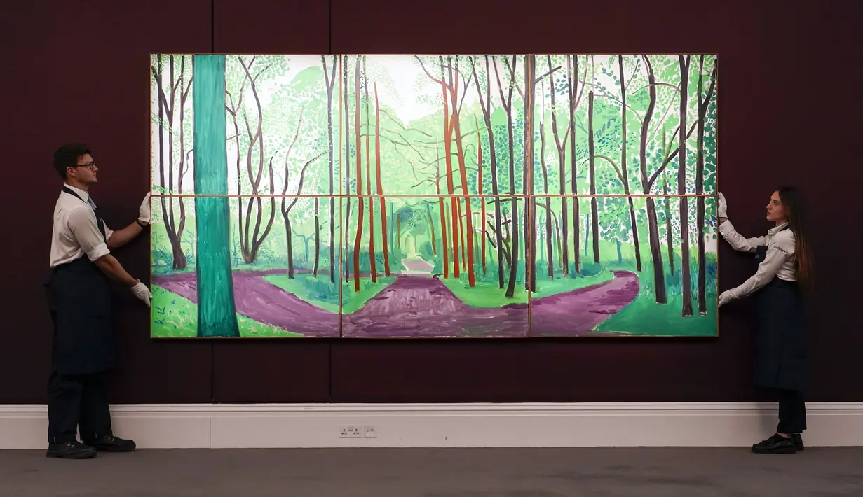 Staf memegang lukisan 'Woldgate Woods II' karya David Hockney di Sotheby's, London, Inggris, 22 Juni 2022. Lukisan yang akan dilelang pada 29 Juni 2022 itu diperkirakan memiliki harga 10-15 juta pound. (AP Photo/Alberto Pezzali)