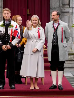 Putri Mahkota Norwegia Mette-Marit, Pangeran Mahkota Norwegia Haakon, dan Pangeran Norwegia Sverre Magnus menyapa pawai anak-anak selama perayaan hari nasional di Skaugum di Asker, dekat Oslo, Norwegia, pada 17 Mei 2026.  (dok. Lise Åserud / NTB / AFP)