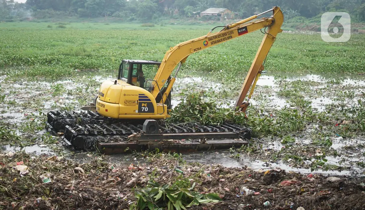 Petugas menggunakan alat berat untuk mengeruk eceng gondok yang memenuhi permukaan Setu Pengarengan, Depok, Jawa Barat, Senin (16/12/2019). Pengerukan dilakukan untuk membersihkan Setu Pengarengan dari eceng gondok yang tumbuh selama kurang lebih satu tahun terakhir. (Liputan6.com/Immanuel Antonius)