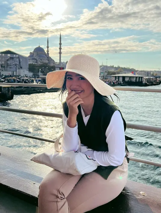 Febby Rastanty memilih daerah dengan cuaca yang lebih hangat untuk berlibur. Seperti terlihat dalam foto ini, Febby Rastanty menghabiskan waktu di Turki dengan tampilan yang chic. Ia mengenakan kaus putih lengan panjang yang ditumpuknya dengan sleeveless sweater berwarna hijau, dipadu dengan celana panjang cokeat, dan topi lebar. Foto: Instagram.