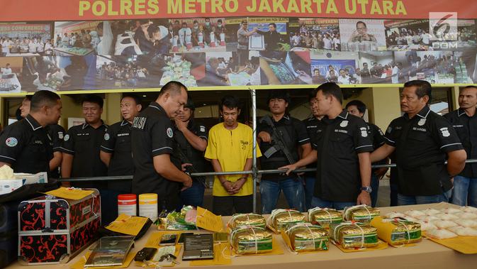 Petugas memperlihatkan tersangka dan barang bukti penyelundupan kasus narkotika jenis sabu di Mapolres Metro Jakarta Utara, Selasa (6/8/2019). Aparat kepolisian mengamankan seorang pengedar berinisial DA pada 27 Juli lalu saat menyelundupkan 10 kg sabu-sabu ke indekos. (merdeka.com/Imam Buhori)